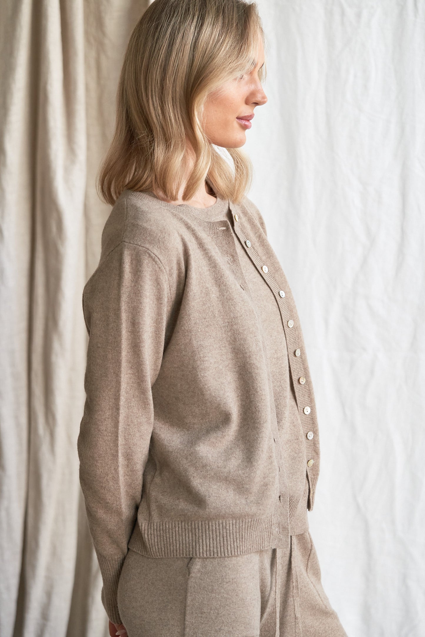 Mushroom Cashmere Cardigan – Women’s Knitwear with Mother-of-Pearl Buttons | 100% Pure Cashmere
Refined and versatile, our mushroom cashmere cardigan is a wardrobe essential for cool weather layering. Made from 100% ethically sourced pure cashmere, this women’s knit features a soft neutral taupe-grey hue and is finished with natural mother-of-pearl buttons for a delicate, elevated touch.
With a relaxed fit and luxurious softness, this cardigan is ideal for work, weekends, or travel. Lightweight yet warm,