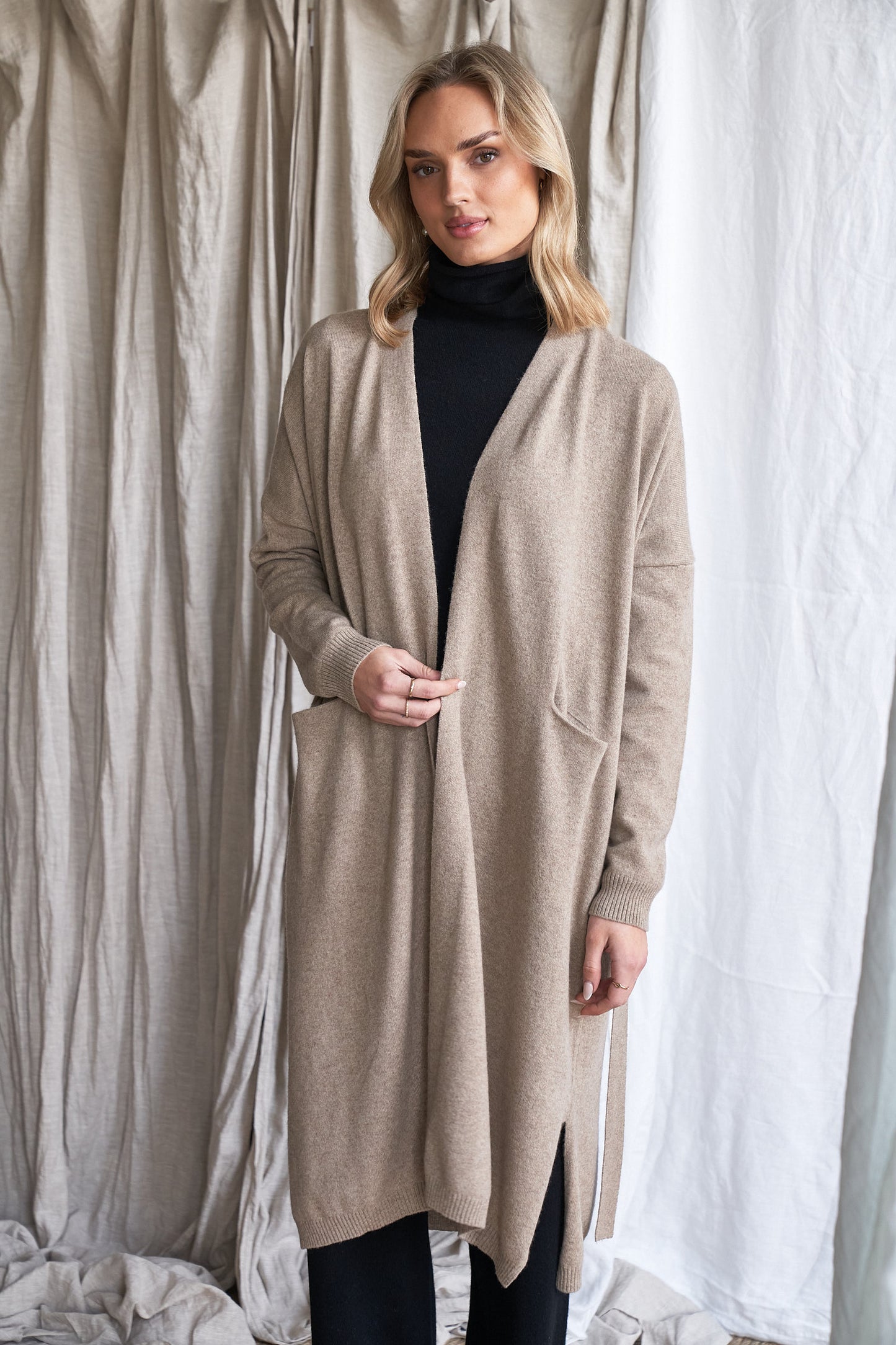 Long Mushroom Cashmere Cardigan with Belt & Pockets – Women’s Coatigan | 100% Pure Cashmere
Wrap yourself in luxury with our long cashmere cardigan in mushroom, designed with a soft belted waist and practical front pockets. Made from 100% pure, ethically sourced cashmere, this elegant coatigan-style knit offers a relaxed, robe-like silhouette perfect for layering during cooler months.
The neutral taupe-grey tone makes it endlessly versatile, while the detachable belt allows for multiple styling options. W